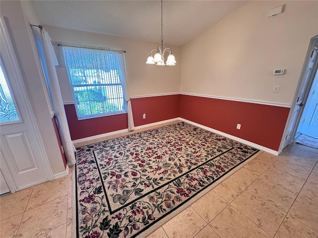 dining area featuring tile patterned floors, a notable chandelier, baseboards, and a textured ceiling