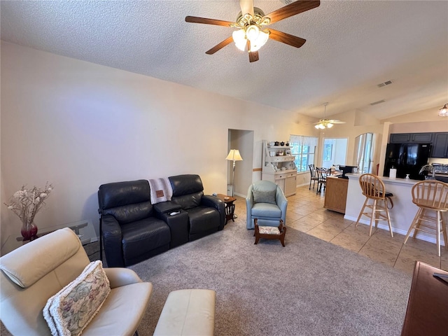 living area featuring light tile patterned floors, visible vents, lofted ceiling, and a ceiling fan