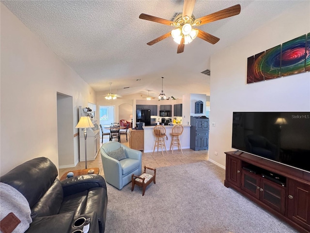 living room with visible vents, a ceiling fan, a textured ceiling, lofted ceiling, and light colored carpet