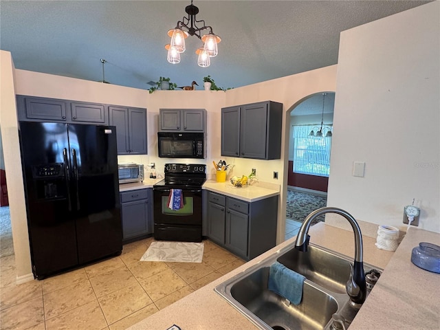 kitchen with a chandelier, light countertops, light tile patterned floors, black appliances, and a sink