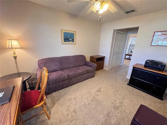 living area featuring ceiling fan, visible vents, carpet floors, and a textured ceiling