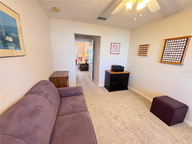 living room featuring a ceiling fan, baseboards, visible vents, a textured ceiling, and carpet flooring