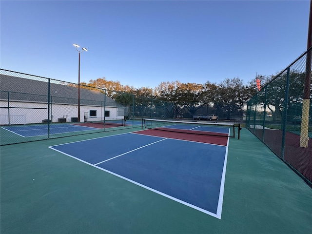 view of tennis court with community basketball court and fence