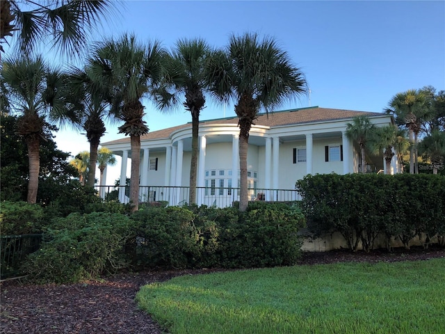 exterior space with stucco siding and a front lawn