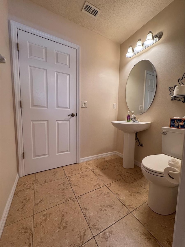 24614 Stillridge Ct, Leesburg, FL 34748 - bathroom featuring a textured ceiling, visible vents, toilet, tile patterned floors, and baseboards