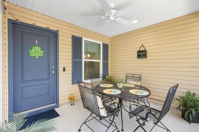 view of exterior entry with ceiling fan, outdoor dining space, and a patio area
