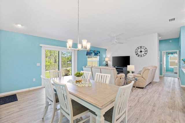 dining area with light wood finished floors, visible vents, baseboards, vaulted ceiling, and ceiling fan with notable chandelier