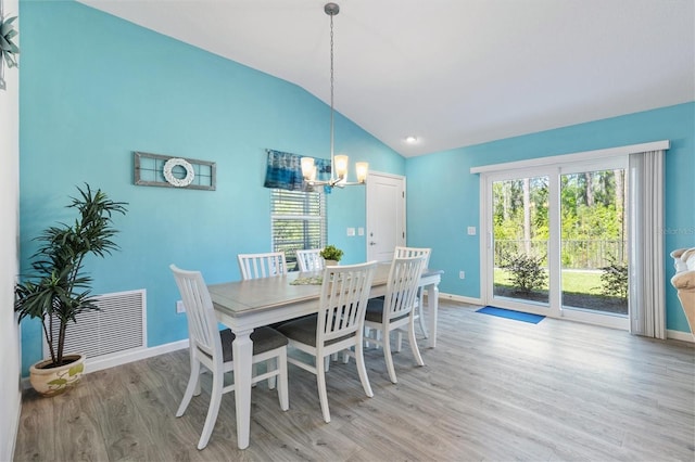 dining space featuring vaulted ceiling, a notable chandelier, a healthy amount of sunlight, and light wood-style floors