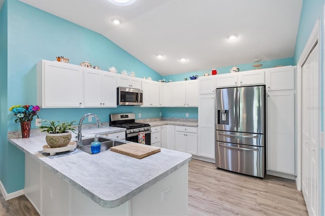 kitchen with a peninsula, a sink, stainless steel appliances, light countertops, and vaulted ceiling