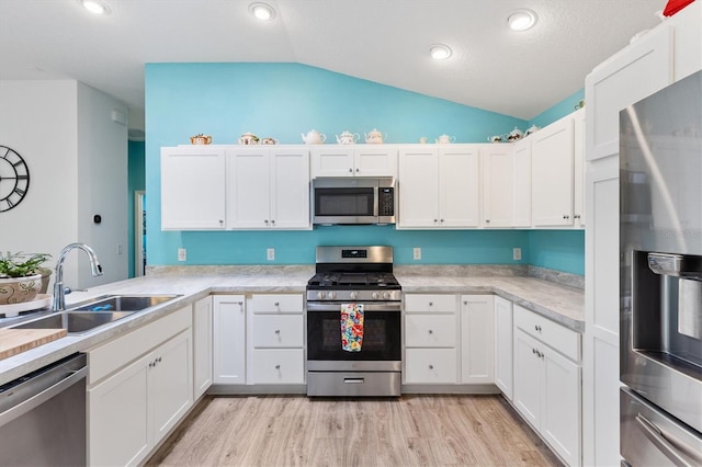 kitchen featuring white cabinets, stainless steel appliances, light countertops, and a sink