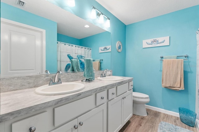 bathroom featuring visible vents, toilet, wood finished floors, and a sink