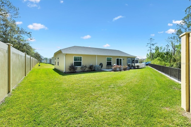 rear view of property featuring a yard, a patio, and a fenced backyard