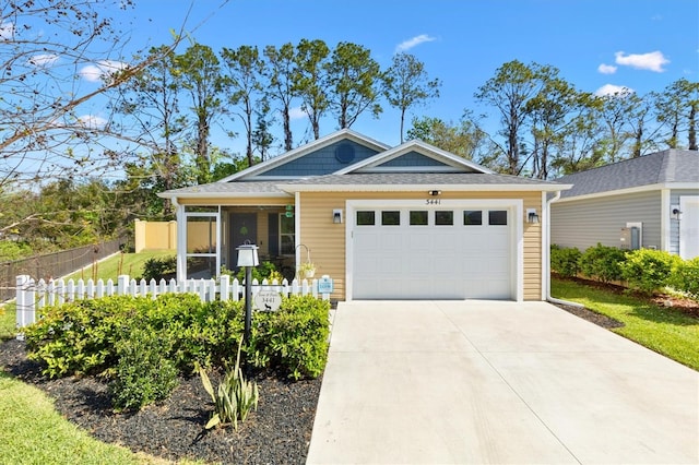 view of front of house with driveway, a garage, and fence