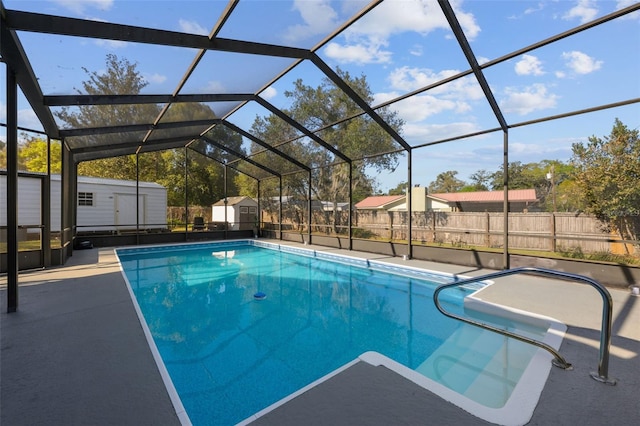 view of pool with an outbuilding, fence, a shed, a lanai, and a patio area