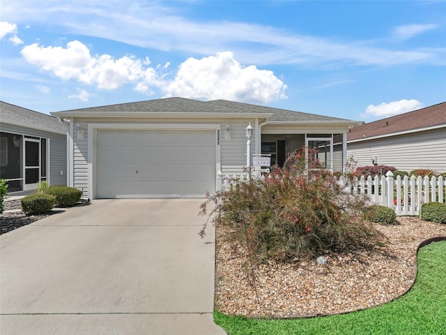 ranch-style house with a garage, roof with shingles, concrete driveway, and fence