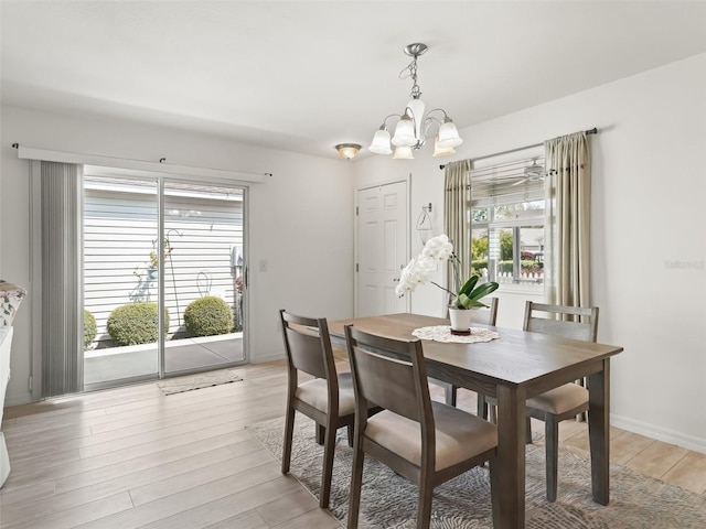 dining space with baseboards, light wood finished floors, and a chandelier