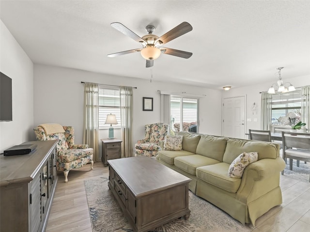 living area featuring light wood finished floors and ceiling fan with notable chandelier