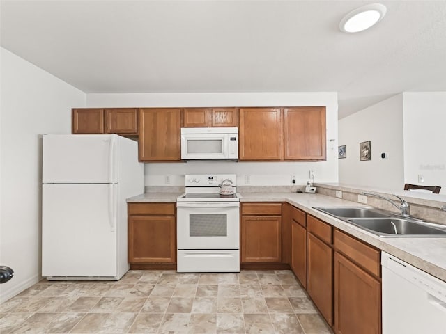 kitchen with brown cabinetry, white appliances, light countertops, and a sink