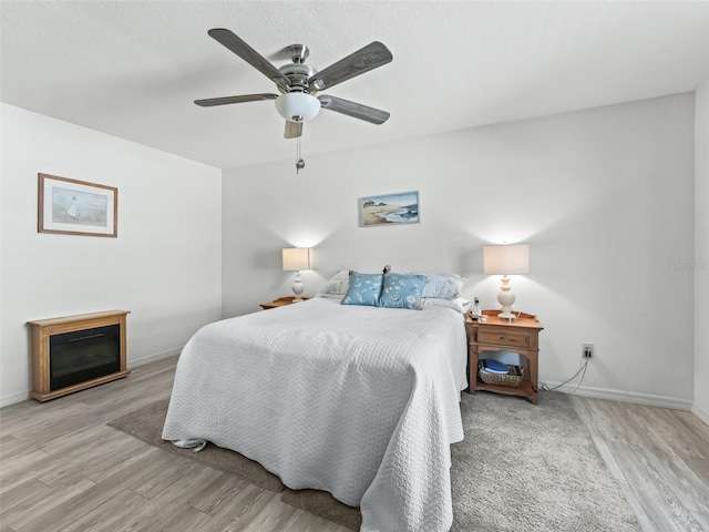 bedroom with a ceiling fan, wood finished floors, and baseboards