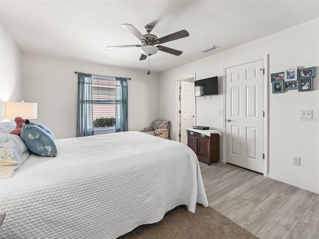 bedroom featuring light wood-style flooring, baseboards, visible vents, and ceiling fan