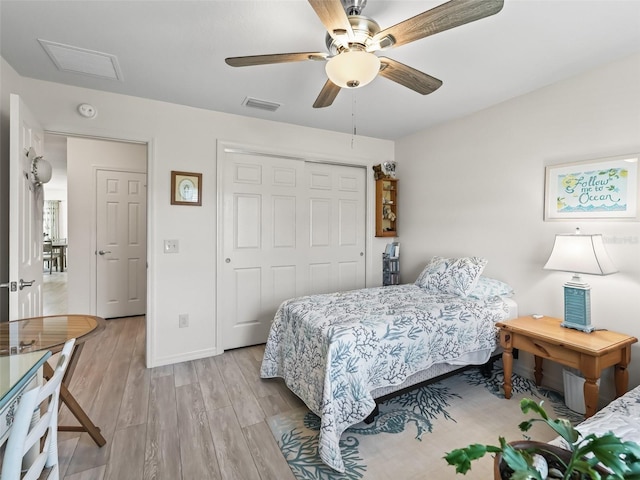 bedroom with a closet, visible vents, light wood-style flooring, and a ceiling fan