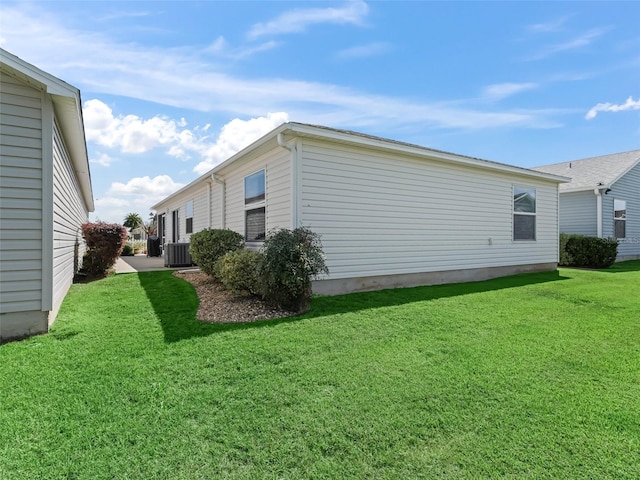 view of side of property featuring central air condition unit and a lawn