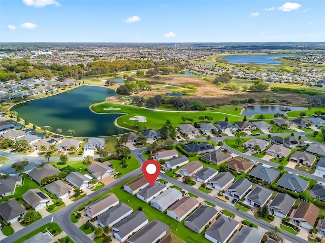 drone / aerial view featuring golf course view, a water view, and a residential view