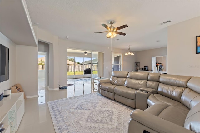 living room with light tile patterned flooring, ceiling fan with notable chandelier, visible vents, and baseboards