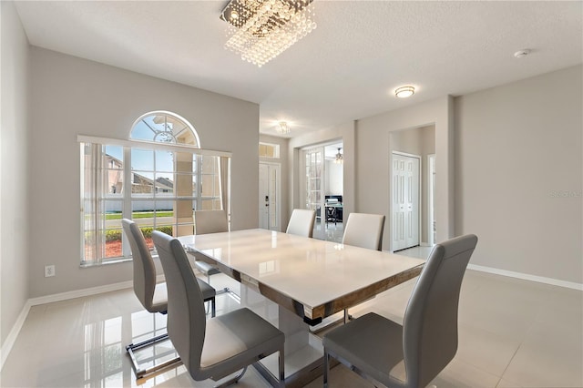 dining room featuring baseboards, a textured ceiling, a healthy amount of sunlight, and a chandelier