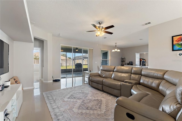 living room featuring visible vents, ceiling fan with notable chandelier, a textured ceiling, and baseboards