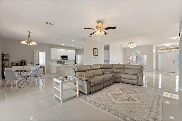 living room featuring visible vents, baseboards, light tile patterned floors, ceiling fan with notable chandelier, and recessed lighting