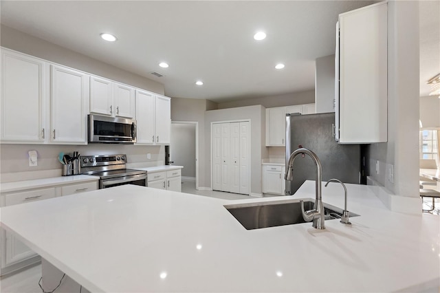 kitchen with a sink, visible vents, white cabinetry, and stainless steel appliances