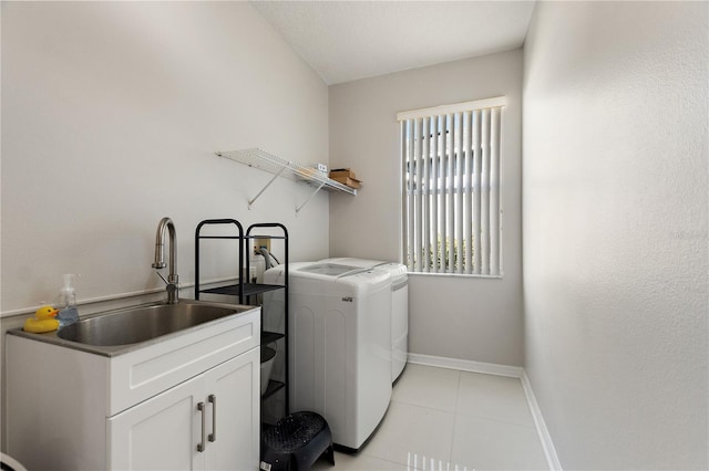 clothes washing area with baseboards, light tile patterned floors, laundry area, separate washer and dryer, and a sink