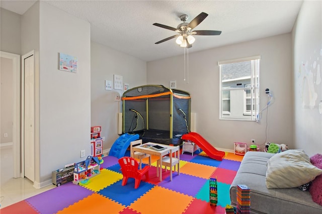 rec room featuring baseboards, a textured ceiling, and a ceiling fan