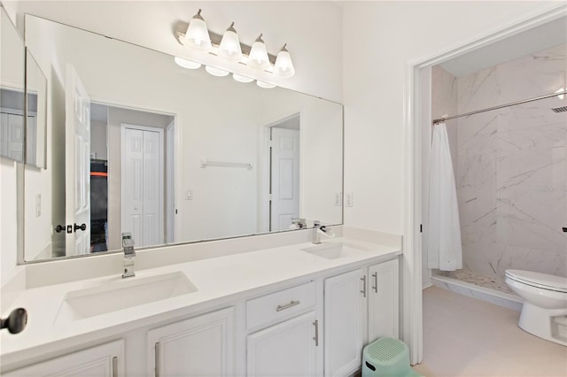 bathroom with double vanity, toilet, a stall shower, and a sink