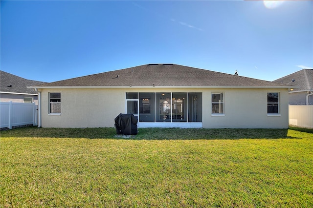 rear view of property featuring a yard, a fenced backyard, a sunroom, and stucco siding