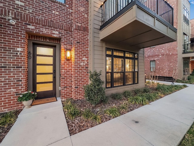 entrance to property with a balcony and brick siding