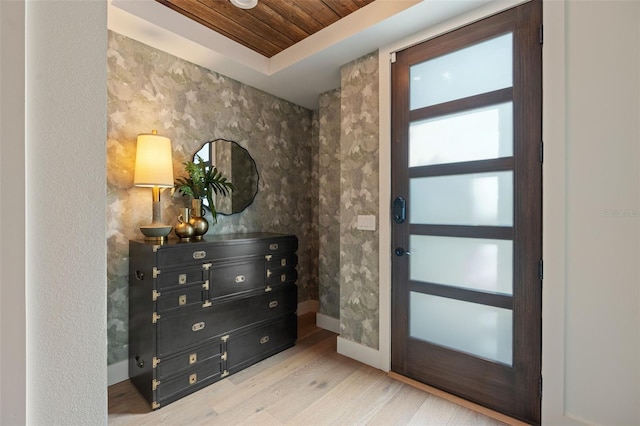 foyer entrance featuring wooden ceiling, wood finished floors, baseboards, and a raised ceiling