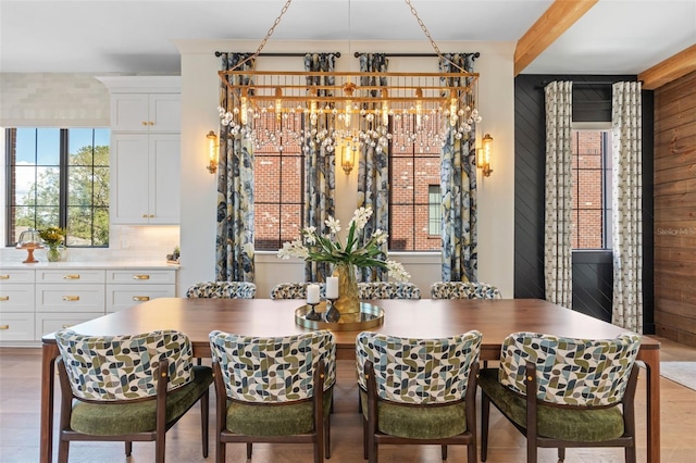 dining area with a chandelier, wooden walls, and beamed ceiling