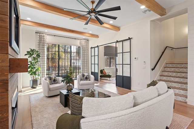 living room featuring visible vents, beamed ceiling, wood finished floors, stairway, and ceiling fan