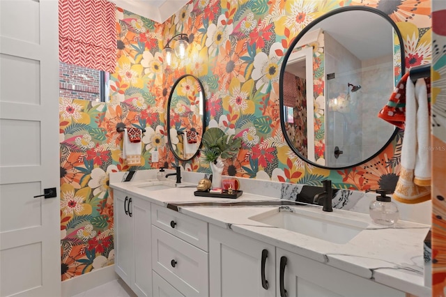 full bathroom with wallpapered walls, double vanity, a tile shower, and a sink