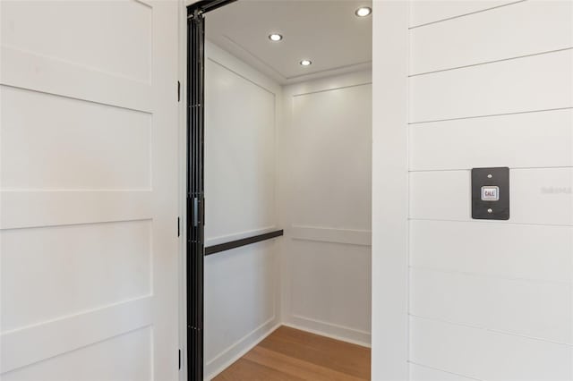 interior details featuring elevator, wood finished floors, and recessed lighting