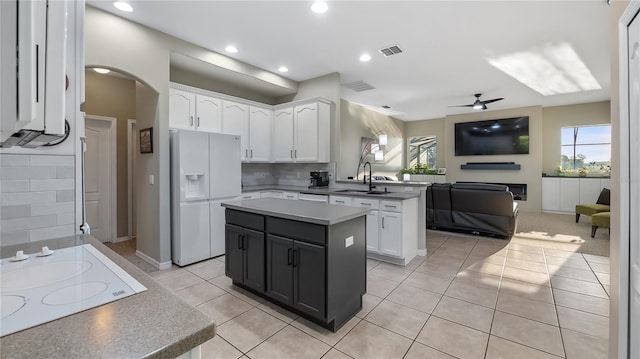 kitchen featuring white appliances, visible vents, a sink, white cabinetry, and open floor plan