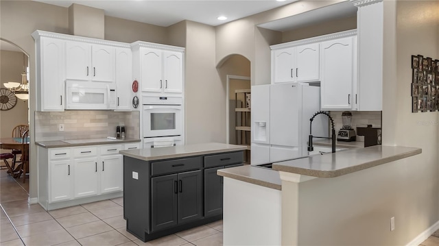 kitchen with white appliances, arched walkways, a peninsula, and white cabinetry