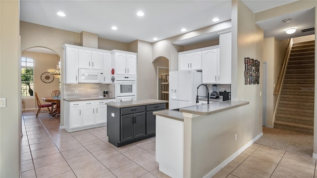 kitchen with white appliances, white cabinets, light tile patterned flooring, and arched walkways