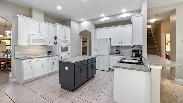 kitchen featuring a sink, white cabinetry, white appliances, arched walkways, and a peninsula