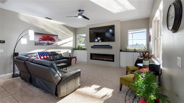 living room featuring a glass covered fireplace, light tile patterned floors, a ceiling fan, and visible vents