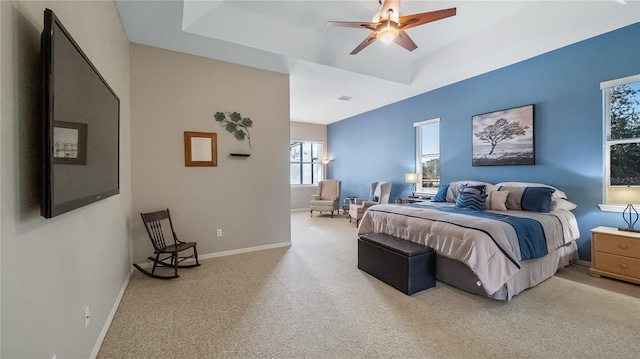 carpeted bedroom with a raised ceiling, baseboards, and ceiling fan