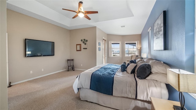 carpeted bedroom featuring a tray ceiling, visible vents, baseboards, and ceiling fan