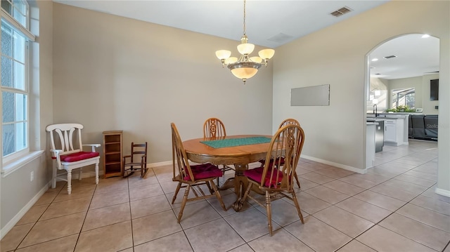 dining space with light tile patterned flooring, visible vents, arched walkways, and baseboards